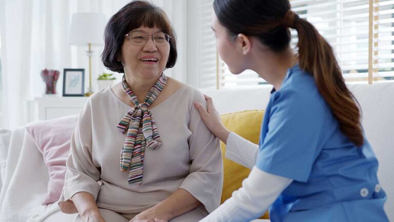 An older adult gently petting a small dog in a cozy apartment living room.
